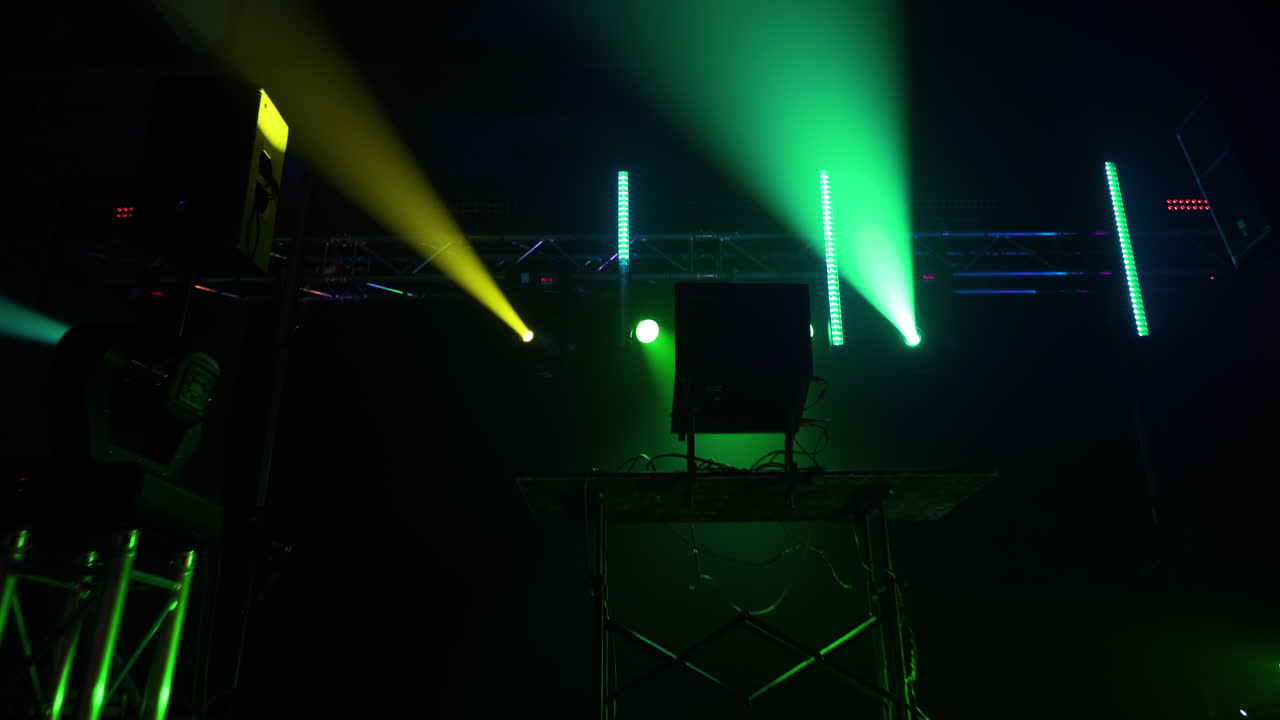 Dolly shot of a DJ stand in an empty warehouse with flashing strobe lights