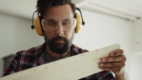 tracking video of carpenter looking at a piece of plank