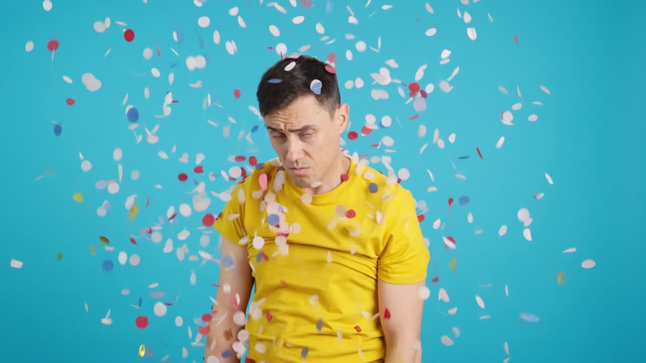 Man covered in confetti looking sad