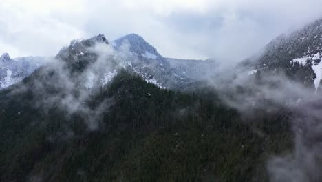 aerial shot pushing into the cascade mountains with wispy clouds in north bend, wa