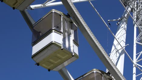 4k. the cabins of a ferris wheel stop and start spinning. amusement park