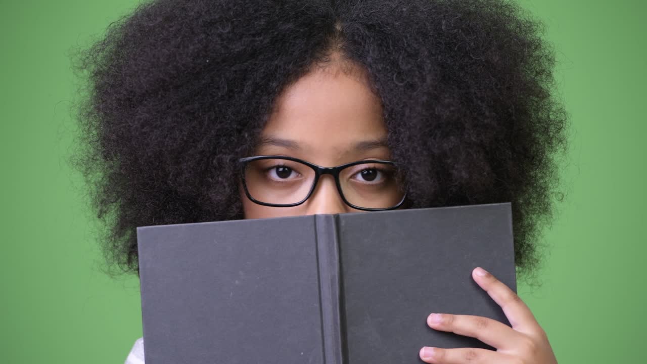 joven chica africana con cabello afro estudiando contra un fondo verde