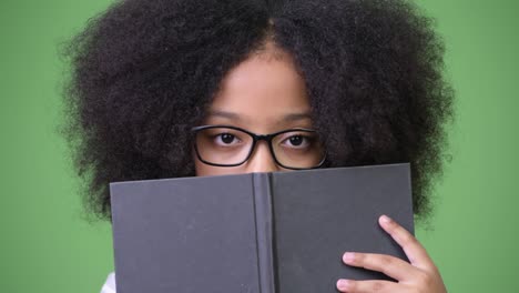 joven chica africana con cabello afro estudiando contra un fondo verde