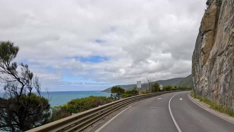 a coastal drive showcasing ocean views, cliffs, and lush greenery under a partly cloudy sky
