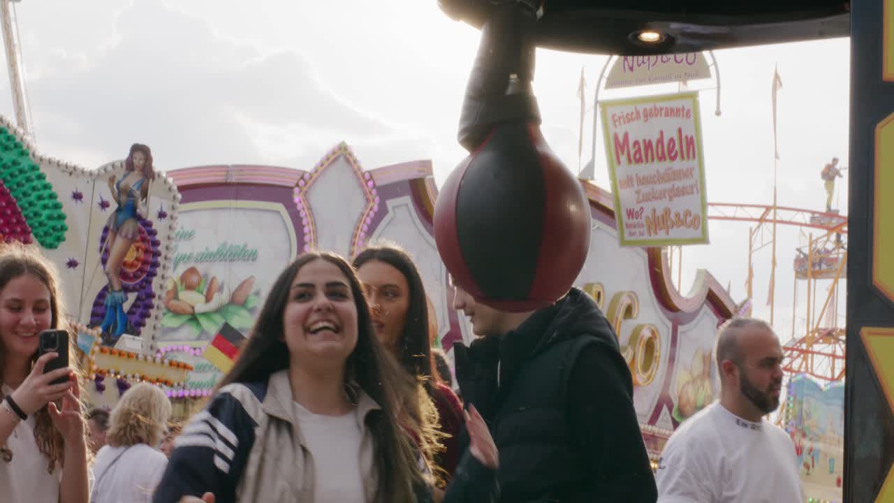 Group of teens punching a boxing bag game at Balvarian outdoor Spring Fest in Stuttgart, Baden Wurttemberg, Germany, Europe, afternoon panning view angle