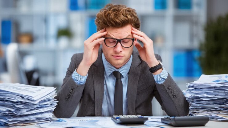 Imprenditore stressato alle prese con un'enorme mole di pratiche burocratiche e calcoli finanziari in un ambiente d'ufficio