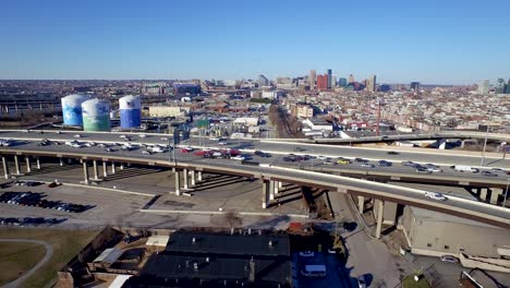 ariel shot moving to the right along interstate 95 during commuter rush hour with the baltimore city skyline in the background