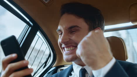 retrato de un hombre de negocios emocionado leyendo buenas noticias en un teléfono móvil en un automóvil.