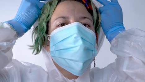 young female doctor putting on the hood of her ppe suit to start fighting covid-19