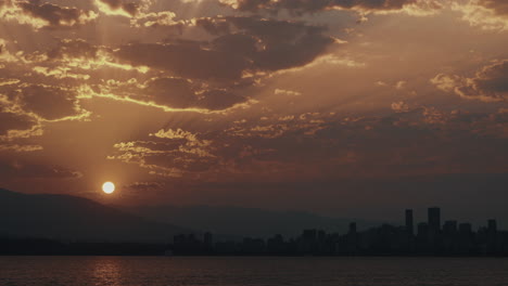 sun rises from mountains over vancouver skyline with beautiful clouds, time lapse