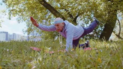 Happy-senior-grandfather-man-exercising,-making-yoga-exercise,-practicing-sports-training-at-park