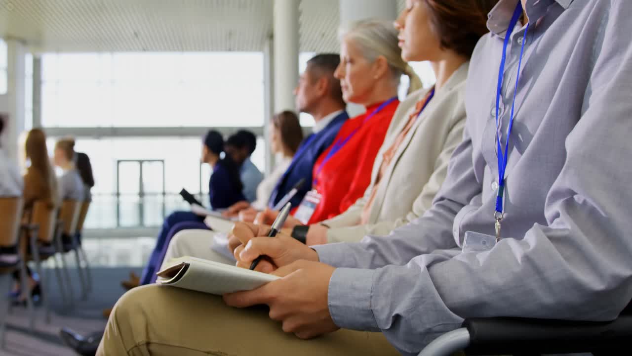 비즈니스 세미나 4k에서 노트패드에 글을 쓰는 비즈니스 사람들