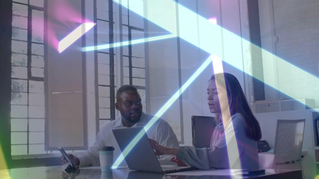 Woman typing on laptop when man using tablet neon beams sweeping across tech desk highlighting data