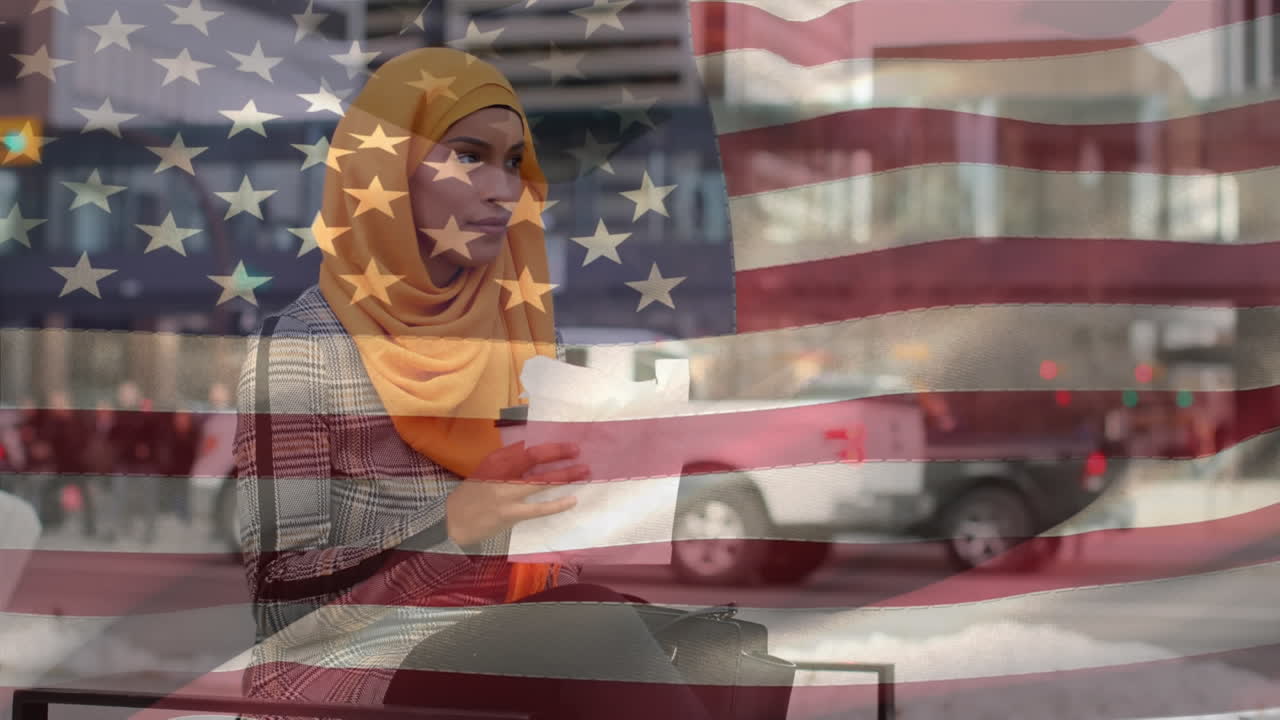 Animation of American flag waving over biracial woman in hijab eating takeaway sandwich