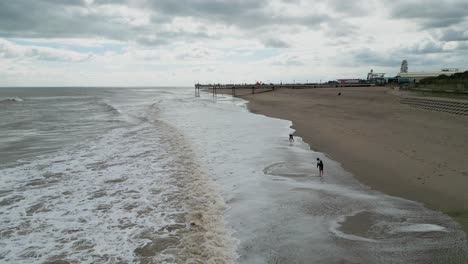 Typischer-Englischer-Badeort,-Aufgenommen-Mit-Einer-Drohne,-Die-Einen-Hohen-Luftbildpunkt-Bietet,-Der-Einen-Weiten-Sandstrand-Mit-Einem-Pier-Und-Tosenden-Wellen-Zeigt-9