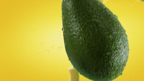 aguacate con rebanadas y salpicaduras cayendo sobre un fondo amarillo