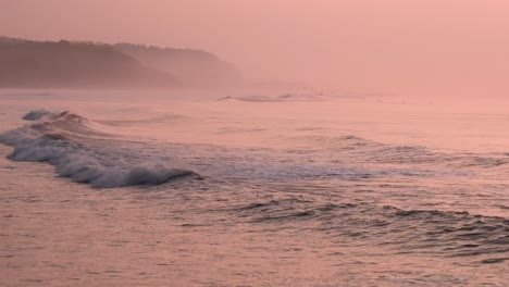 Pelicans-flying-over-the-soft-waves-at-sunset-on-at-Punta-Mango-El-Salvador,-Handheld-shot