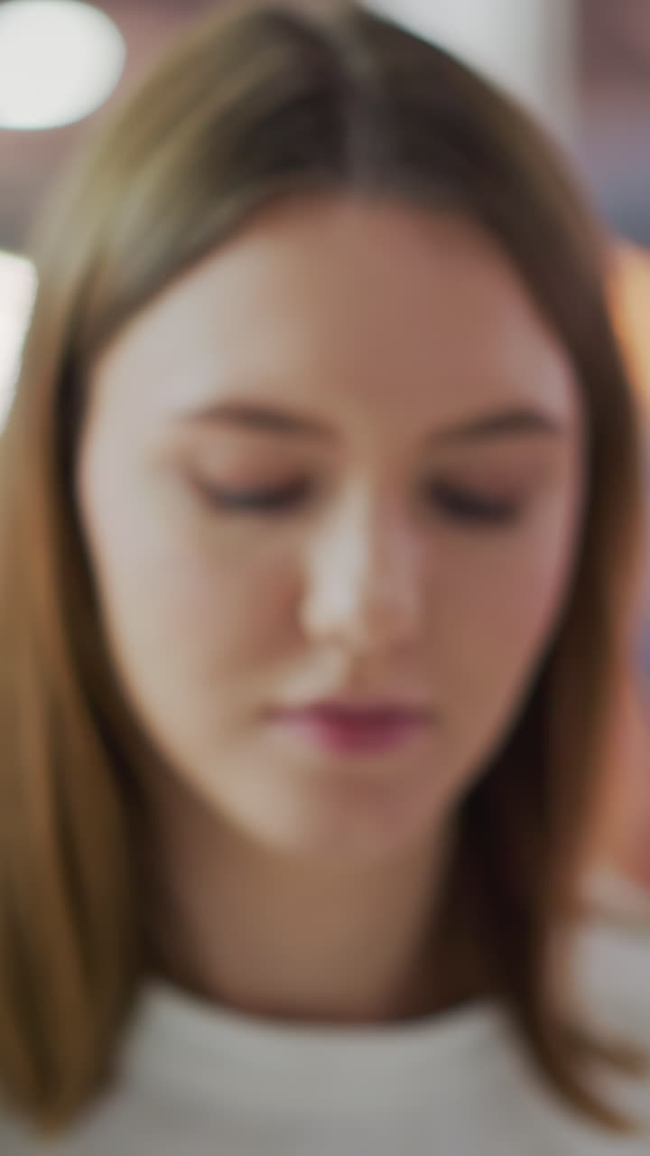 primer plano de una joven pensativa con expresión suave, enfoque ligeramente borroso, ambientado contra un fondo borroso y colorido con luces vibrantes que crean un estado de ánimo sereno e introspectivo