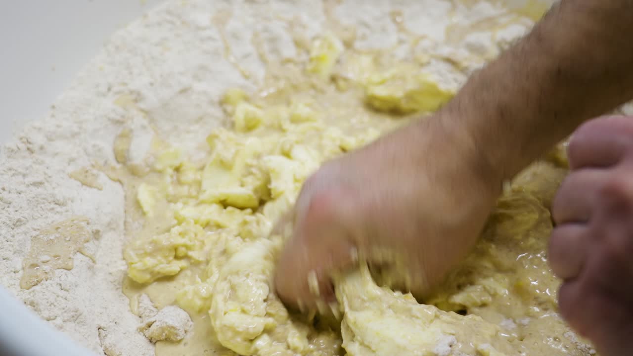 primer plano de las manos mezclando harina, mantequilla y líquido para preparar la masa para la navidad húngara bejgli