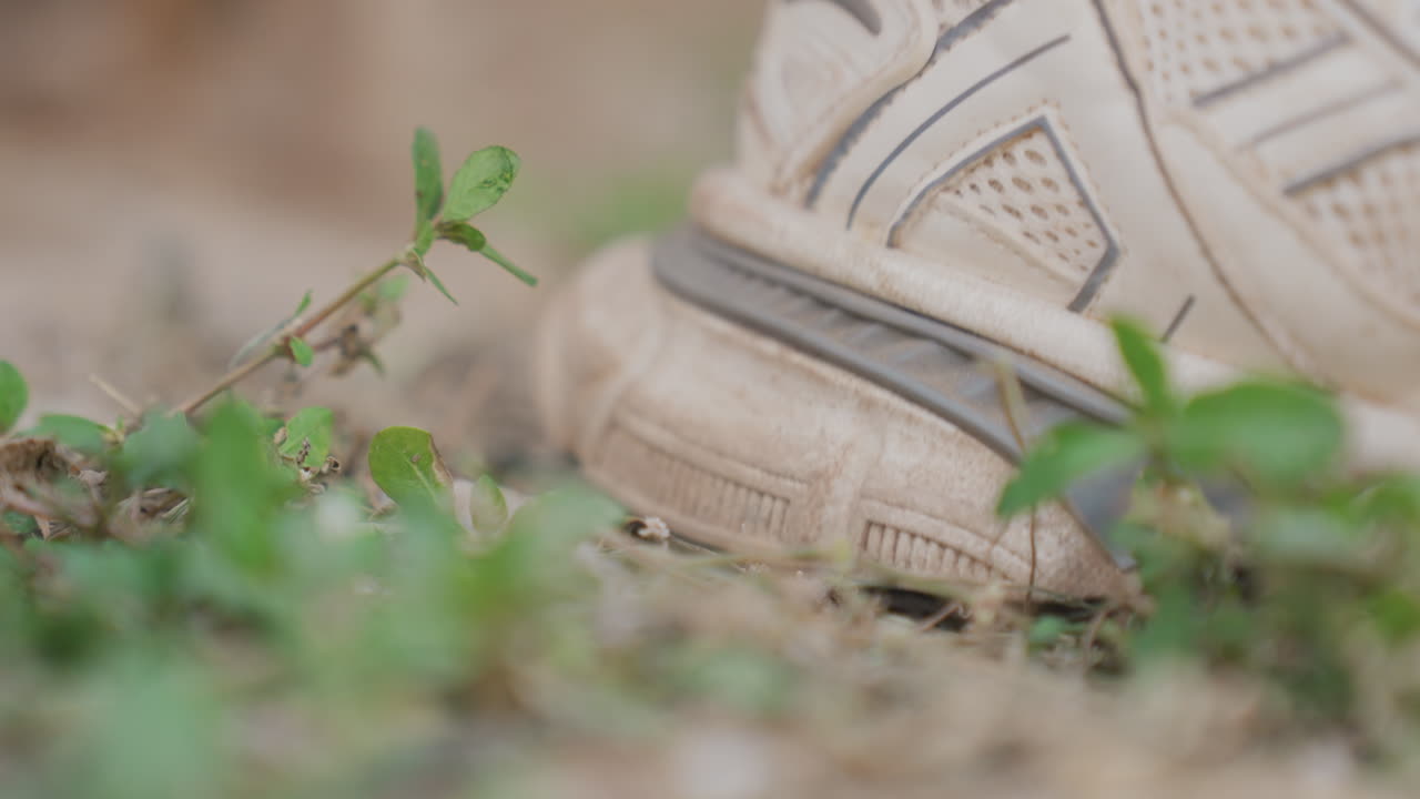 Closeup trainer heel lifting from green ground, quick energetic motion, dust particles dislodging, focused sole grip, athletic stride during outdoor training, lowangle framing, bokeh background