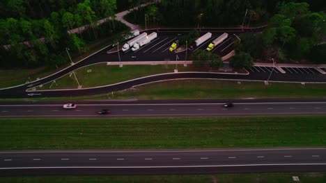 Crane-shot-semi-truck-rest-area-in-Florida-with-highway,-Transportation-concept