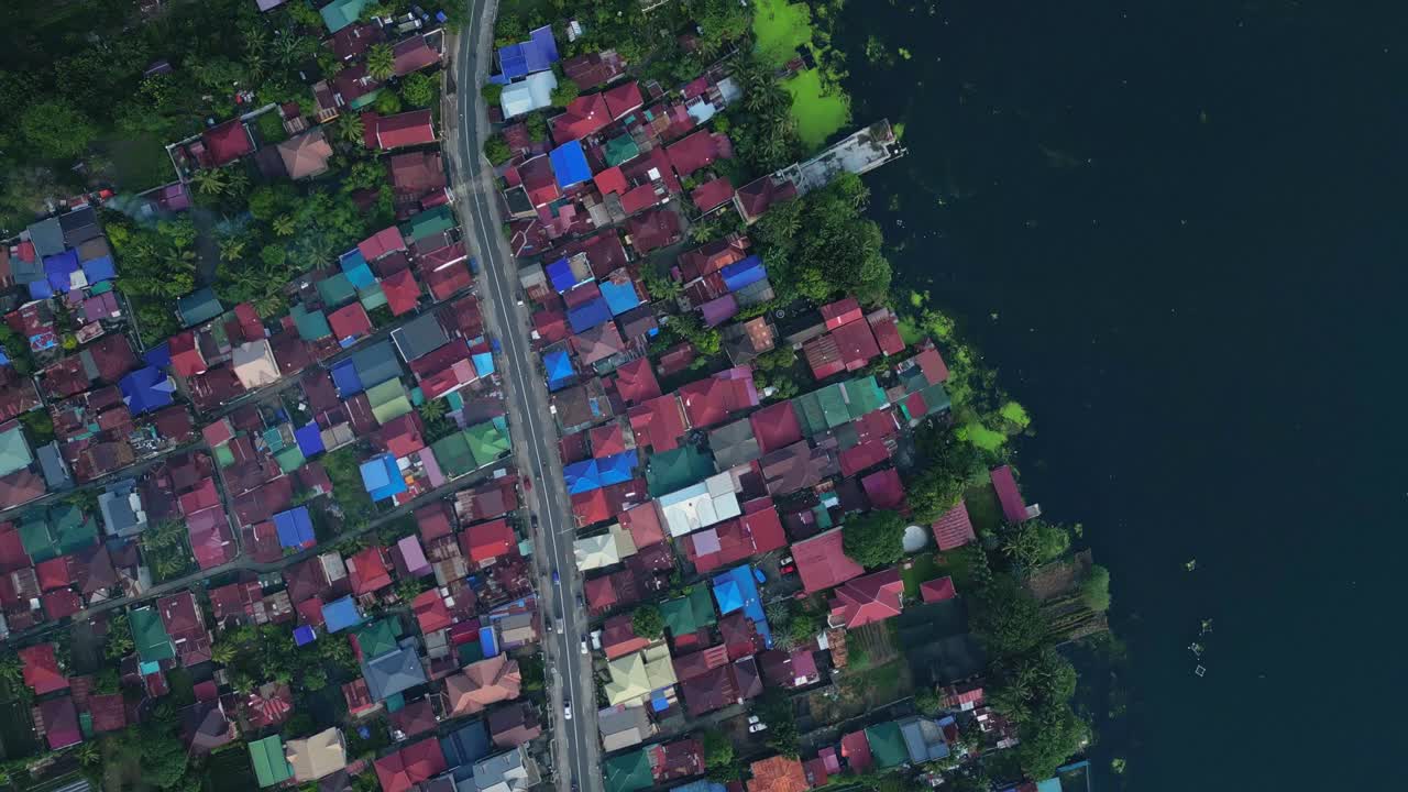 A top-view aerial of the main Talisay town with colorful rooftops lining the lakeside edge of Taal Lake in Batangas, Philippines