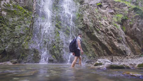 Man-walking-barefoot-in-front-of-waterfall.