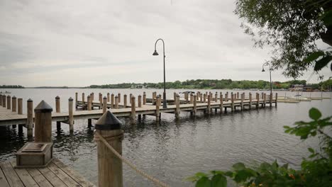 wide push-in shot past a tree, revealing a wooden boat dock with multiple bays