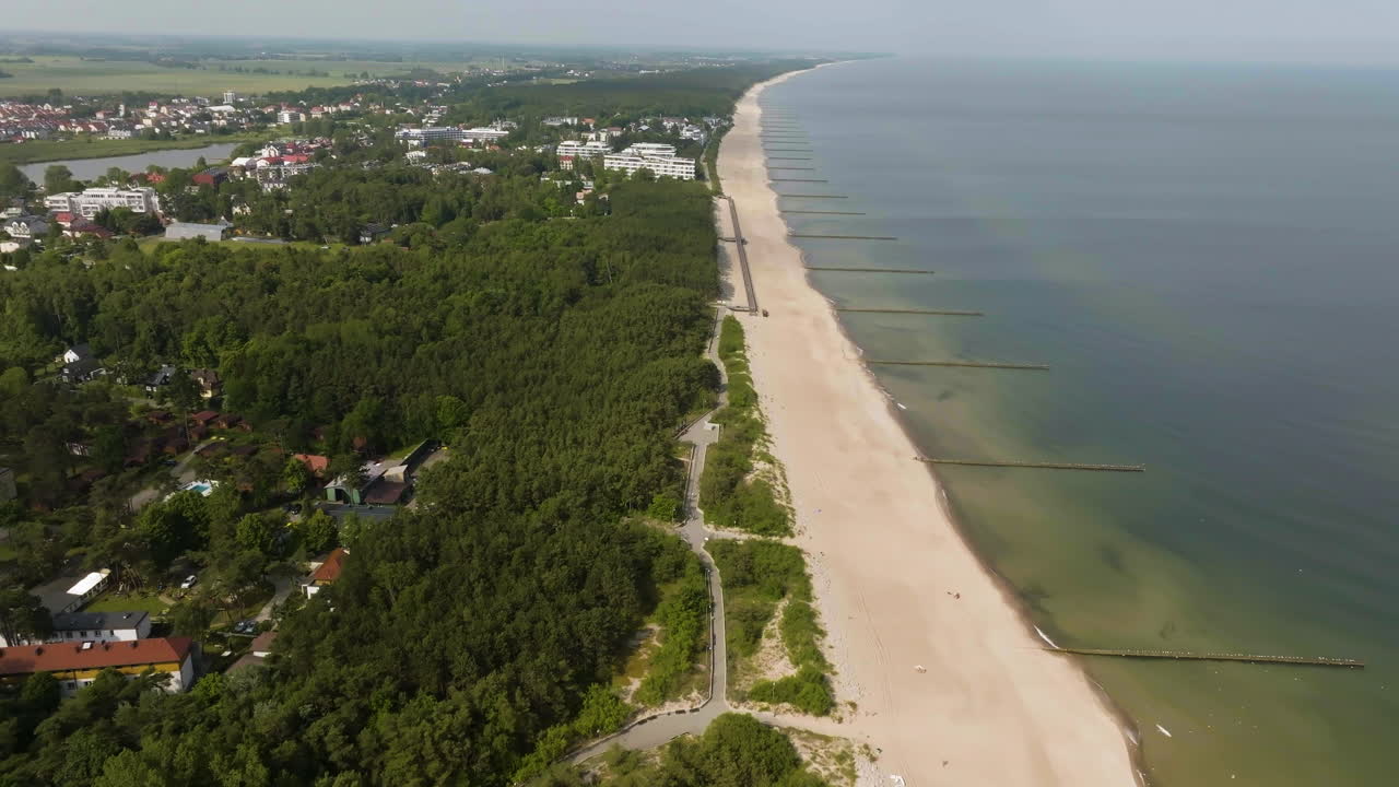 Drone tilting along the promenade at Plaza Mielno beach, summer day in Poland