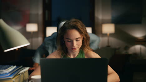 smart woman explaining laptop night closeup. disguised scream mask man sneaking