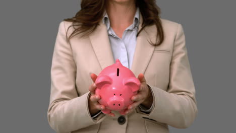 businesswoman throwing a piggy bank on grey screen