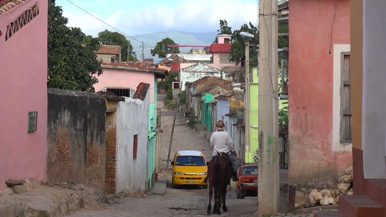 Una bella ripresa degli edifici e delle strade acciottolate di Trinidad, Cuba, con un cowboy che passa a cavallo.
