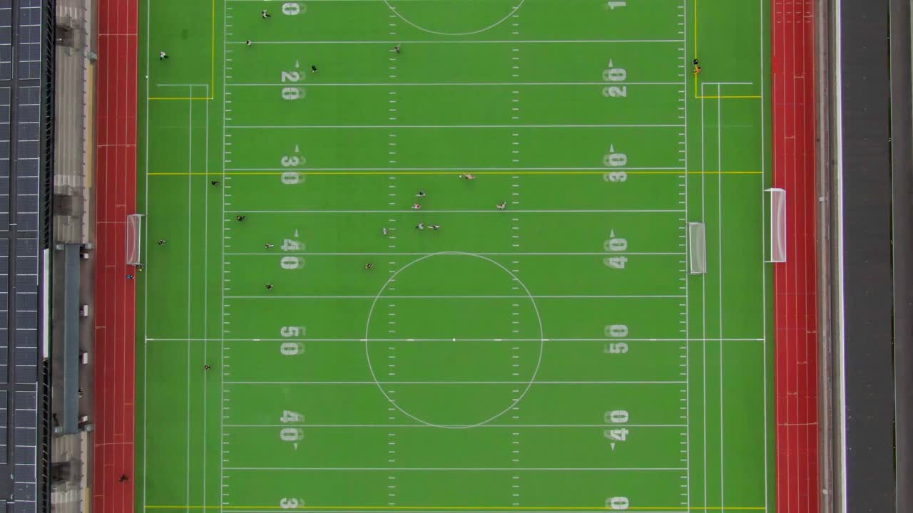 Top-down aerial shot over a small arena, capturing players in action on the football field