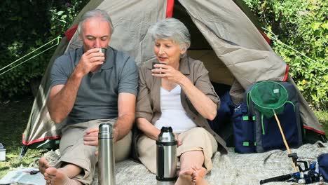 seniors drinking coffee sitting near a tent