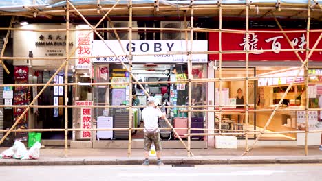 workers repairing storefront under bamboo scaffolding