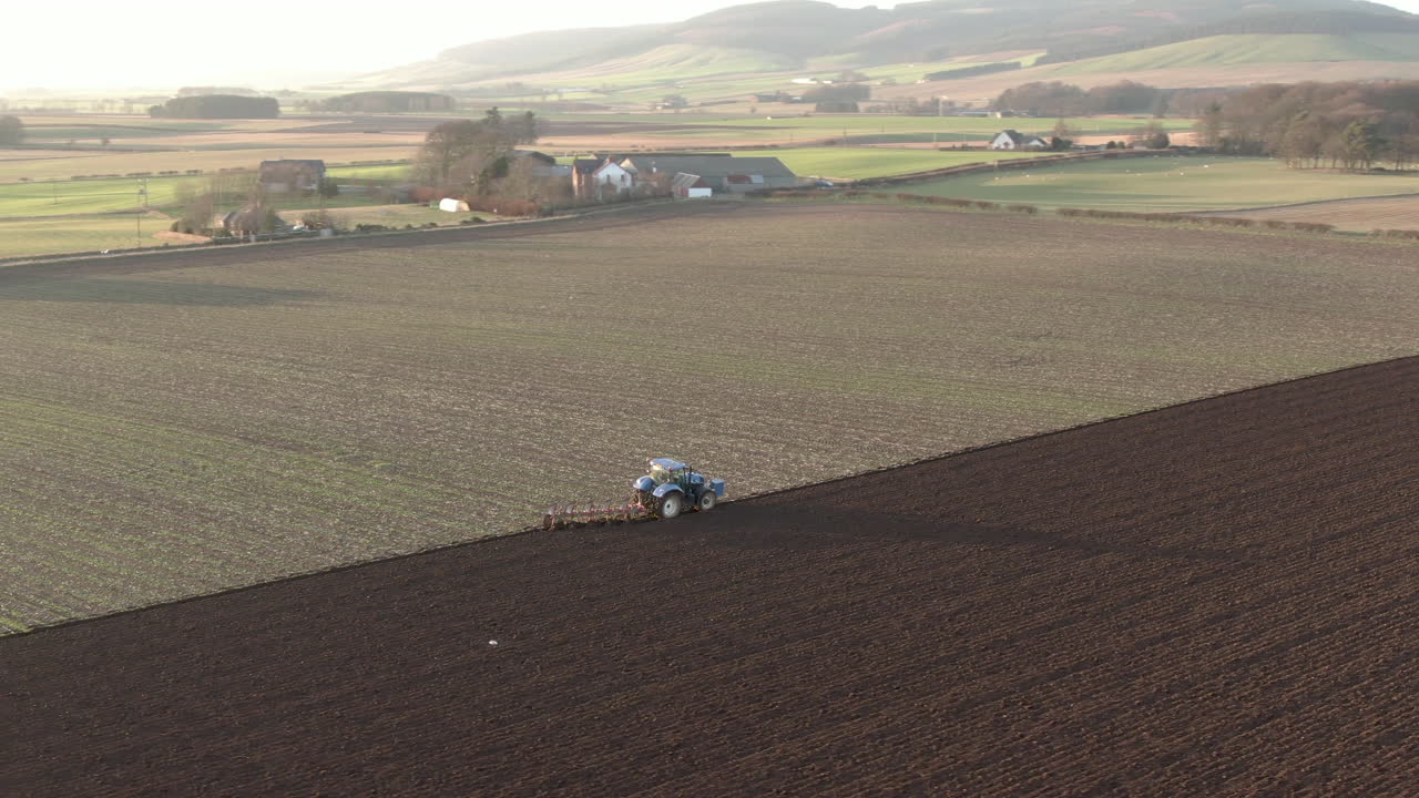 Vista aerea di un trattore agricolo che ara un campo ad Aberdeenshire in una giornata di sole, Scozia