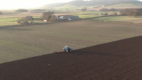 aerial view of a farm tractor ploughing a field in aberdeenshire on a sunny day, scotland