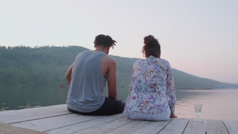 una pareja disfrutando de la vista del lago y hablando en el muelle.