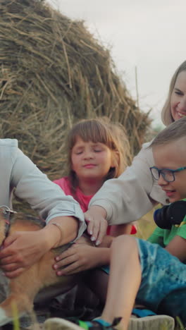 mujer y su hija con niños jugando con un perro con correa al aire libre, sonriendo alegremente cerca de la bala de heno en el campo abierto, reunión familiar casual durante la hora dorada