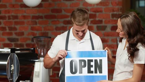 waiter and customer holding a board with open sign