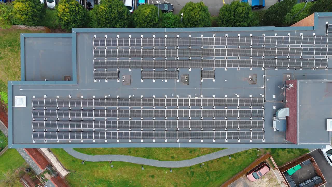 This aerial view shows solar panels on the roof, surrounded by cars and greenery, highlighting sustainable energy use and eco-friendly urban infrastructure.