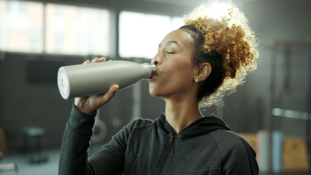 mujer bebiendo agua después del entrenamiento