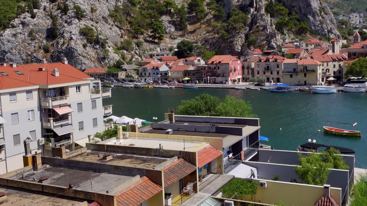 Vista panoramica a mano libera della città di Omis, Croazia, che mostra il fiume, persone, automobili e case.