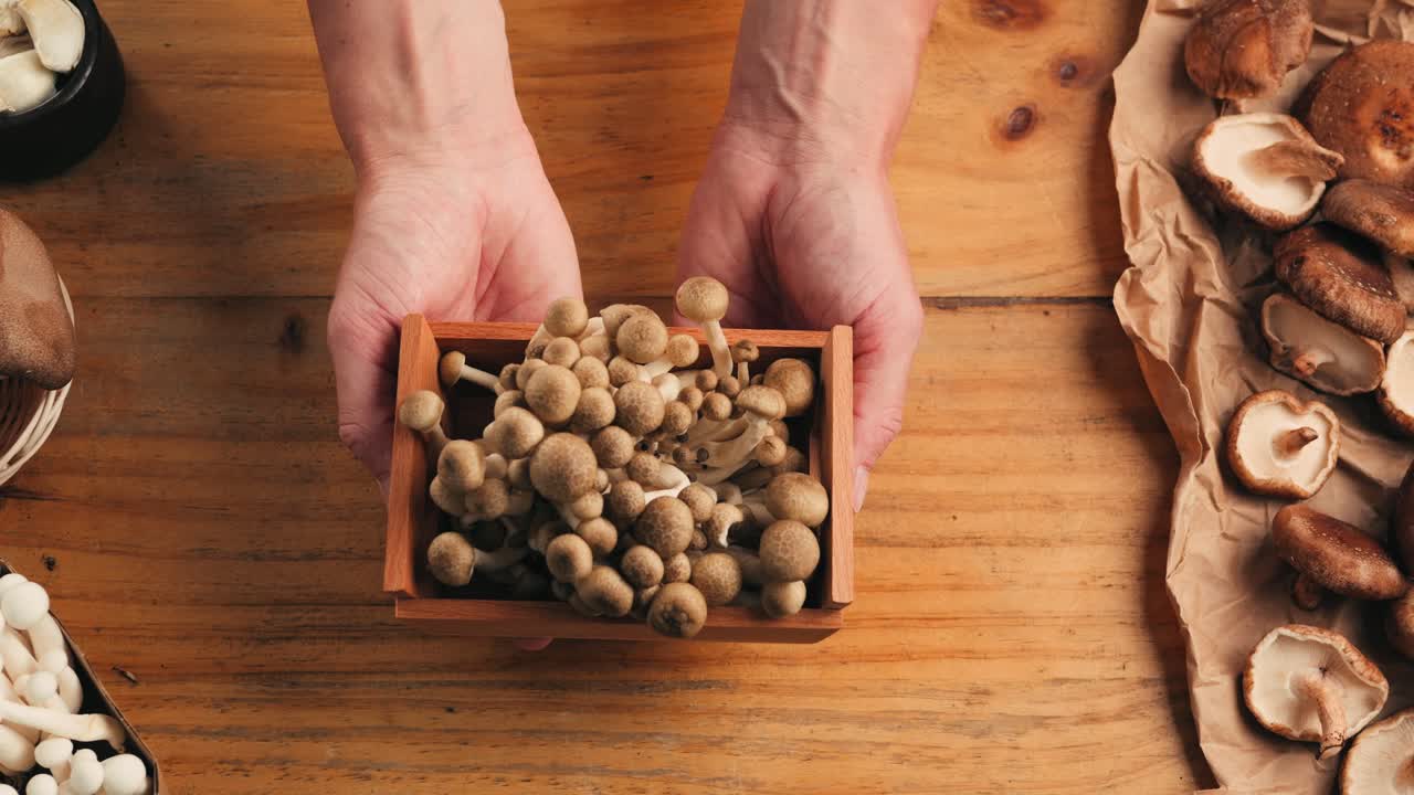 Hands holding a wooden box of mushrooms