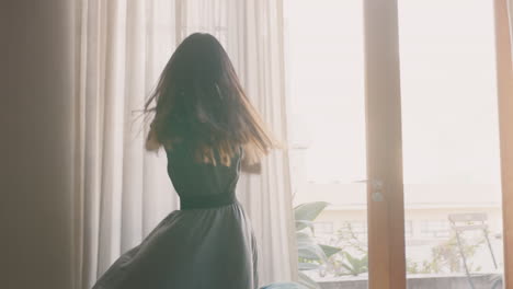 happy young woman dancing at home having fun celebrating summer vacation enjoying playful dance to celebrate successful lifestyle