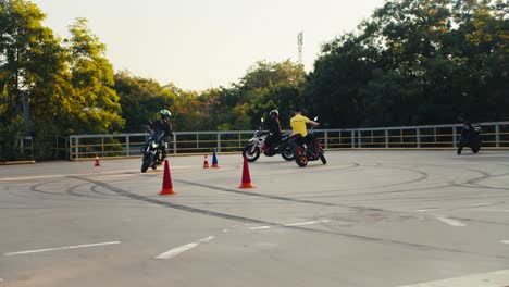 biker students, together with their instructor in a yellow t-shirt, ride around the training ground in a motorcycle school