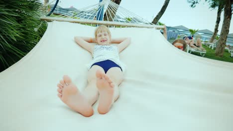 a little girl shakes her older sister on a hammock, having fun during the summer holidays