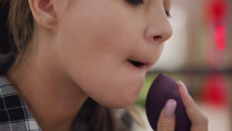 close-up of woman blending powder around mouth and jaw using a beauty sponge, smooth application enhances facial features and blurred background create a professional beauty look