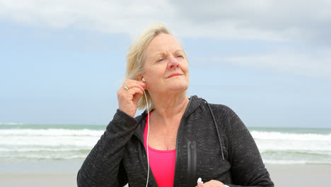 front view of old caucasian senior woman listening music on earphones at beach 4k