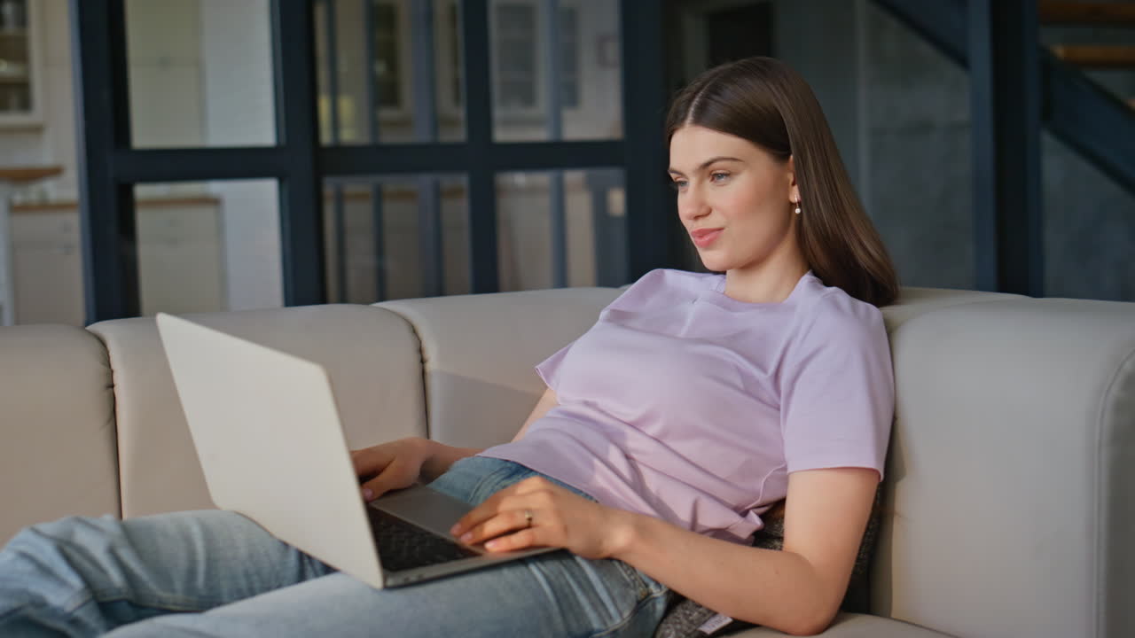 Smiling student texting laptop lying sofa closeup. Lady typing computer online